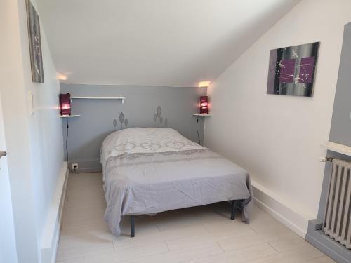 a bed in a room with two lights on the wall at La tour de Plumont in Dole