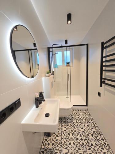 a white bathroom with a sink and a mirror at Haustory Deluxe Apartment in Klaipėda