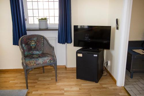 a living room with a chair and a flat screen tv at Hotel Chaplin in Landskrona