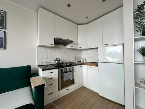a kitchen with white cabinets and a white refrigerator at Mazury Witaj in Ostróda