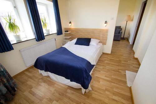 a bedroom with a bed with a blue blanket and two windows at Hotel Chaplin in Landskrona