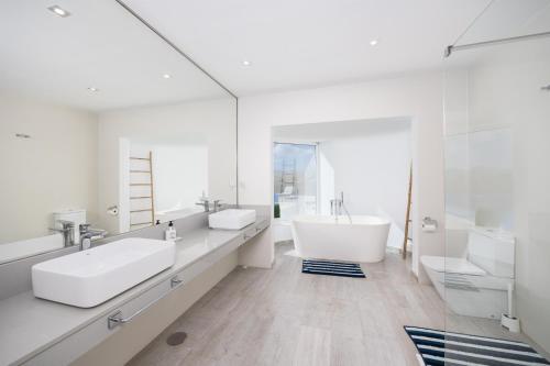 a white bathroom with two sinks and a tub at The View in Tías