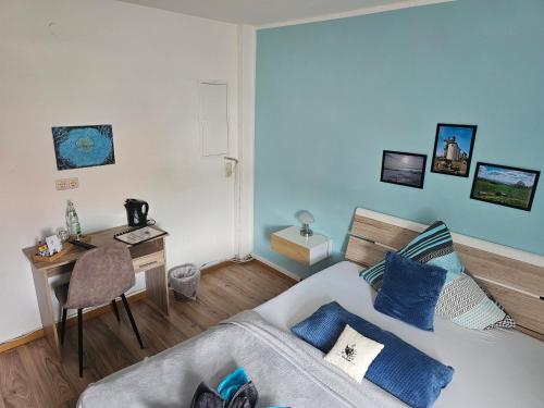 a bedroom with a bed with blue pillows and a desk at Pension Heuhexe in Fladungen