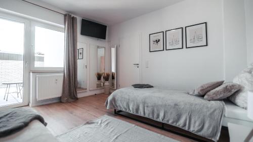 a white bedroom with a bed and a large window at FlexHome Stadtnatur Ferienwohnung in Lippstadt