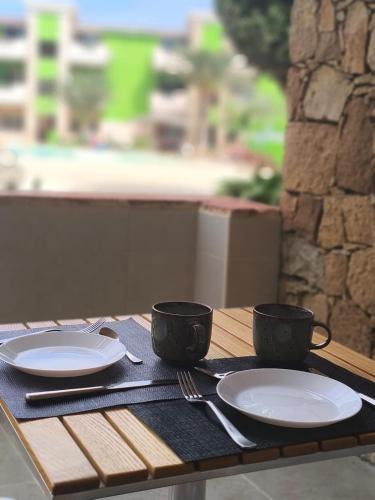 Una mesa de madera con dos tazas y platos encima. en HostySpot - Bloco Verde, en Santa Maria