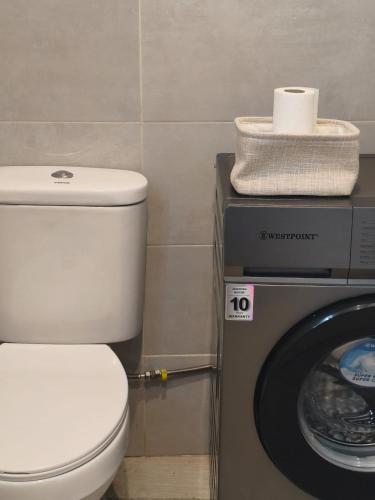 Un baño con inodoro y lavadora. en HostySpot - Bloco Verde, en Santa Maria