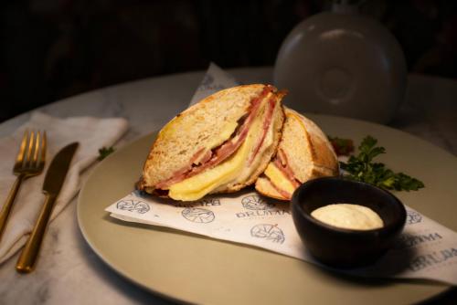 a sandwich on a plate on a table with sauce at Hotel Ambala Bogota Colonial in Bogotá