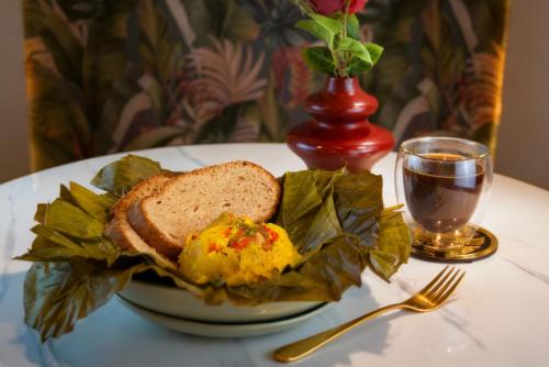 a plate of food with bread and eggs and a glass of wine at Hotel Ambala Bogota Colonial in Bogotá