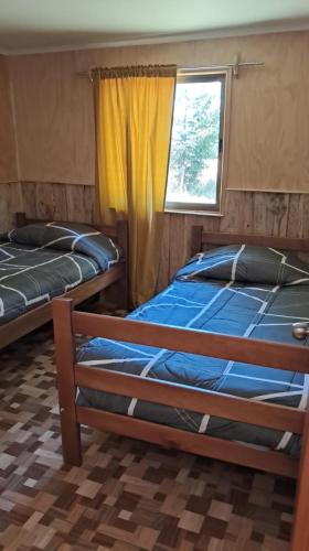 two beds in a room with a window at Paraíso Rustico 3 in Curacautín