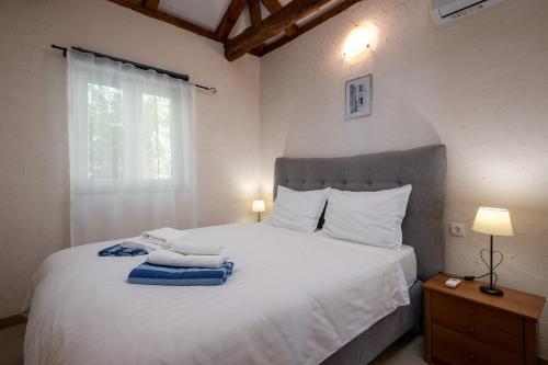 a bedroom with a white bed with towels on it at South Estate in Čilipi