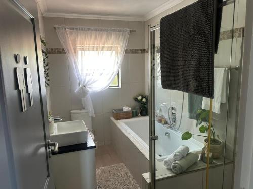 a bathroom with a tub and a sink and a shower at Chasing Jacuzzi Sunsets sea and mountain views in Hermanus