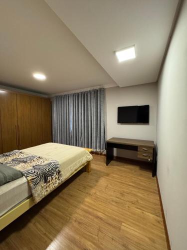 a bedroom with a bed and a flat screen tv at Quarto para locação em apartamento in Conselheiro Lafaiete