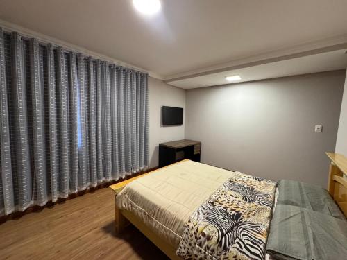 a bedroom with a bed and a window with curtains at Quarto para locação em apartamento in Conselheiro Lafaiete