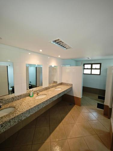 a bathroom with three sinks and two mirrors at Park Golf Hostel Ipelandia in Foz do Iguaçu