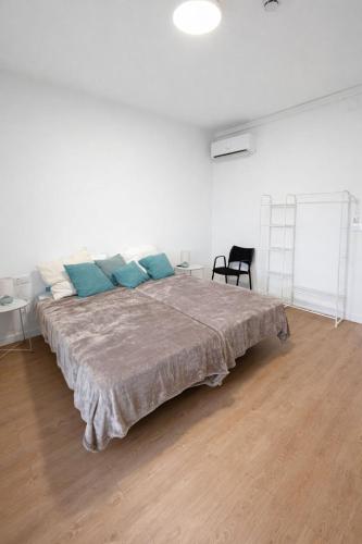 a large bed with blue pillows in a white room at Apartaments Montseny in Girona