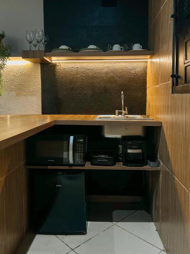 a kitchen with a sink and a microwave at Espaços Cardoso, GRÊS - refúgio sólido e silencioso in Igrejinha