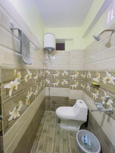 a bathroom with a toilet and flowers on the wall at The Cruze - Premium Hotel in Gulzārbāgh