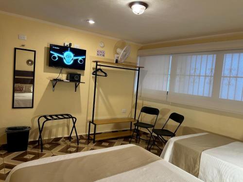 a room with two beds and a tv on the wall at Casa 3 Torres en el Barrio Santiago, Centro. in Mérida