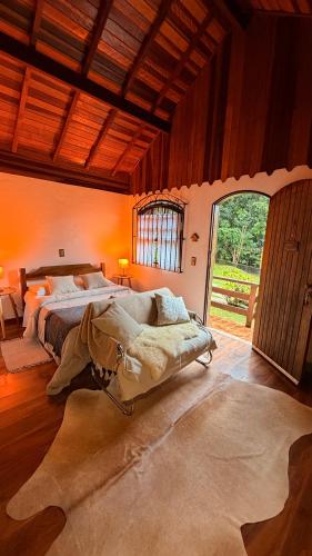 a bedroom with a large bed and a large window at Chalés Lua de Mel in Monte Verde