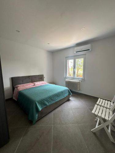 a bedroom with a bed and a window and a chair at Appartamento relax 5-4-3 in Rivalta Bormida