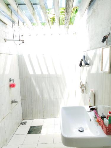a white bathroom with a sink and a shower at Vinal Inn Midigama in Midigama East
