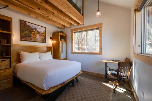 a bedroom with a bed and a desk and a window at Anasazi Cliffs Lodging in Apple Valley