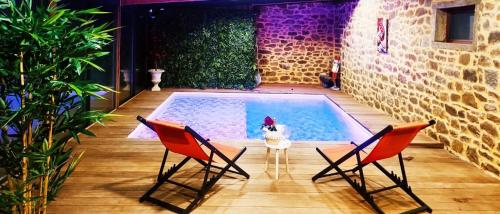 a swimming pool with two chairs and a table at Jacuzzi XXL avec La Rouyonnaise in Tinténiac