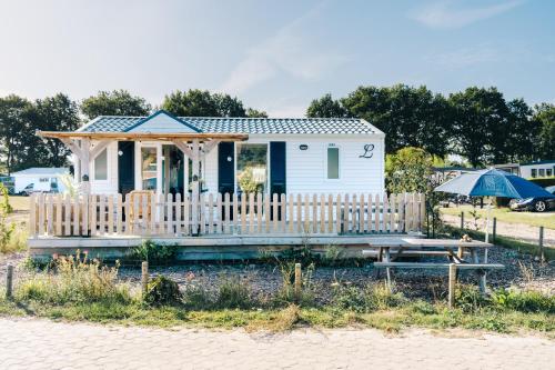 a small white house with a picnic table and an umbrella at Louisiana in Anloo