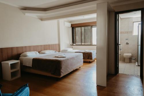 a bedroom with two beds and a bathroom with a shower at Hotel Letto Caxias in Caxias do Sul