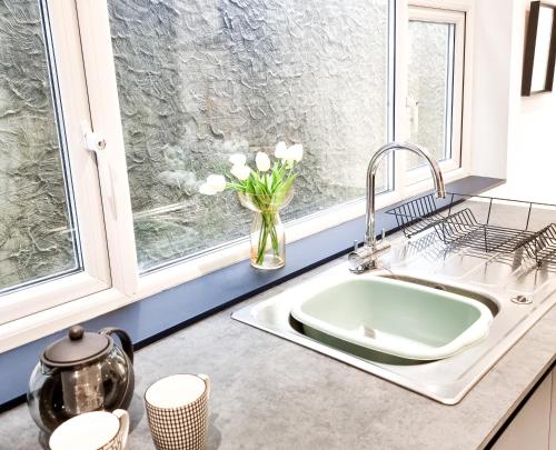 a kitchen sink with a vase of flowers in a window at Urban Escape Stylish 3BR in Swansea in Swansea