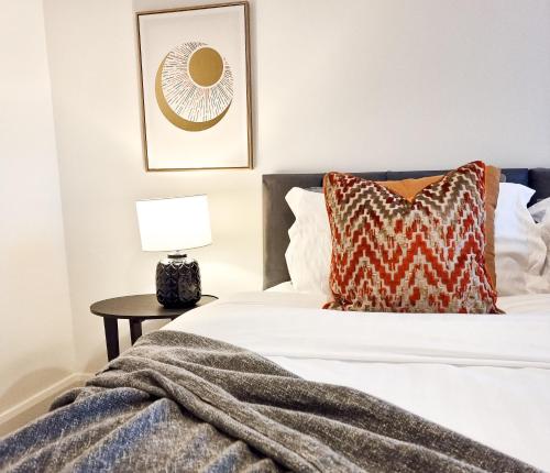 a bedroom with a bed and a table with a lamp at Urban Escape Stylish 3BR in Swansea in Swansea