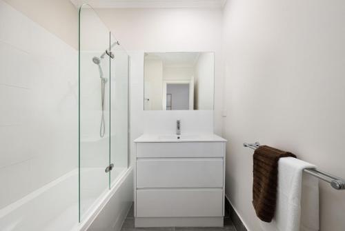 a white bathroom with a sink and a shower at Sundance steps to Half Moon Bay in Black Rock North