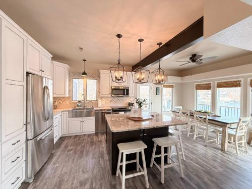 a kitchen with white cabinets and a kitchen island with chairs at Mimosa Mornings Home for 12 in Rocky Mount