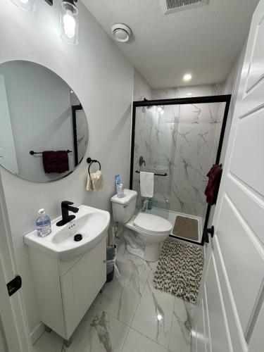 a bathroom with a sink and a toilet and a mirror at Fowler Road Cozy Lower Suite in Airdrie