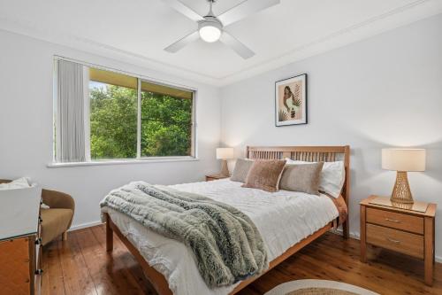 a white bedroom with a bed and a window at Salt & Sand - Flynn's Beach in Port Macquarie