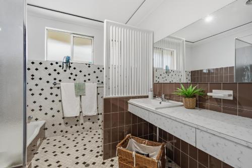 a bathroom with a tub and a sink and a mirror at Salt & Sand - Flynn's Beach in Port Macquarie