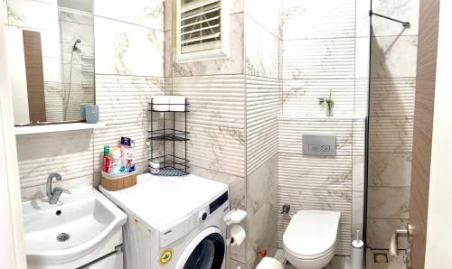a bathroom with a toilet sink and a washing machine at Theos Holiday Apartments Room 23 Family Suit Accommodation For Families Only in Kuşadası