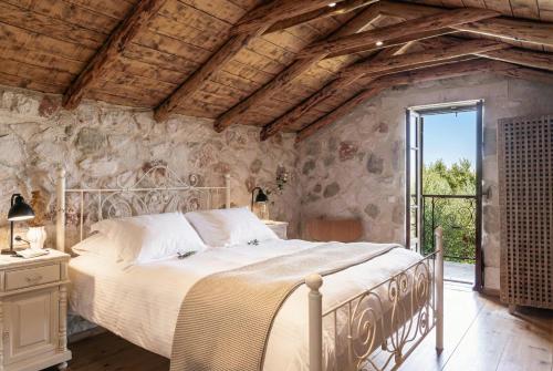 a bedroom with a large bed in a stone wall at Paliokaliva Apartments and Villas in Tsilivi