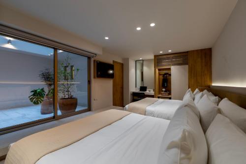 a bedroom with two beds and a large window at Capitalia Reforma Chapultepec in Mexico City
