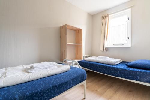 a bedroom with two beds and a window at Appartement De Bosrand, Resort Amelander Kaap in Hollum