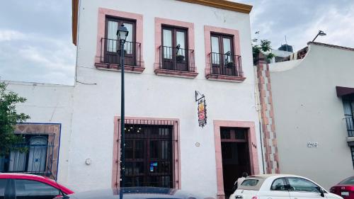 a white building with balconies and cars parked in front of it at Cinco de Mayo Hotel in Querétaro