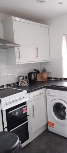 a kitchen with white cabinets and a washing machine at Lilypad in Devizes