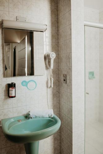 a bathroom with a green sink and a mirror at Hotel Letto Caxias in Caxias do Sul