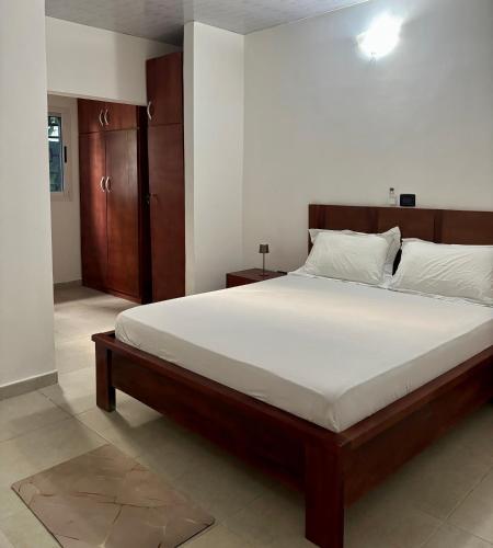 una camera da letto con un letto grande con lenzuola bianche di Villa 308 a Abidjan