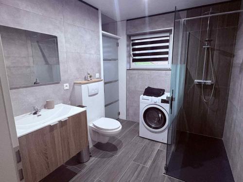 a bathroom with a washing machine and a washer at Le Paradis d'Ayli in Aywaille