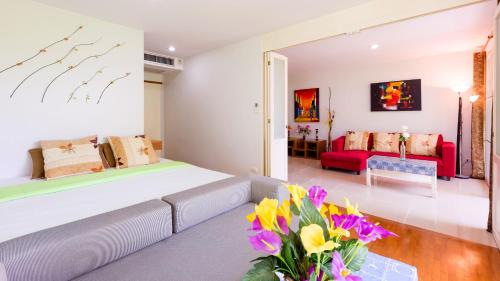 a living room with a bed and a couch and flowers at Baan Poolom Beachfront Condominium in Hua Hin