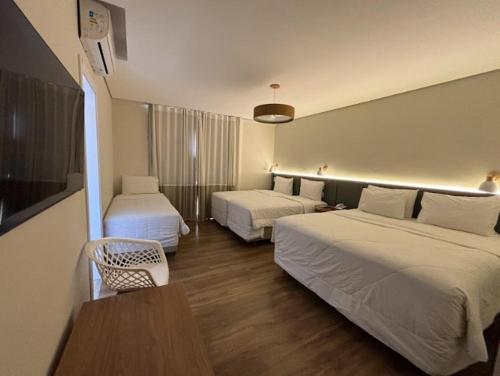 a hotel room with two beds and a table at Hotel Fazenda Brisa Itu in Itu