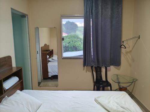 a bedroom with a bed and a mirror and a window at Hotel Mourão in Guanhães