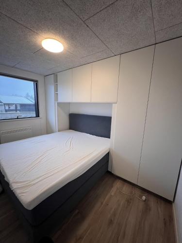 a small room with a bed with white cabinets at House with a lovely location in Børkop