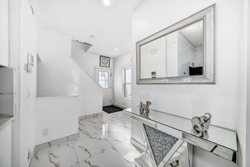 a white hallway with a mirror and a glass floor at Cozy Vacation Home in Calgary
